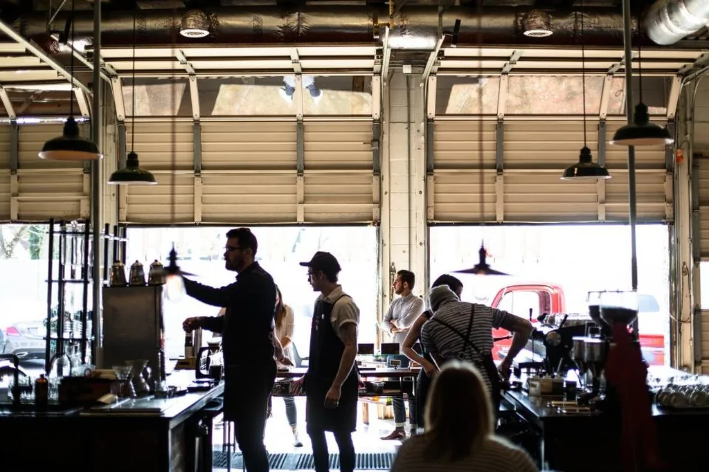 Staff and customers at a cafe with its garage door open