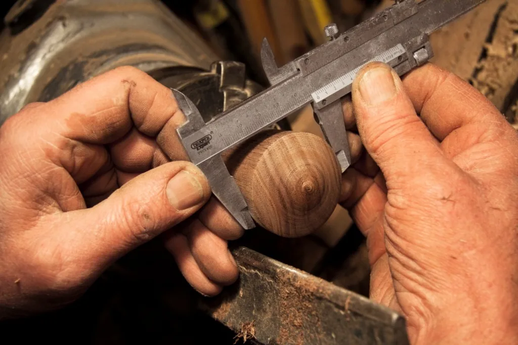 A woodworker measuring a turned piece with calipers