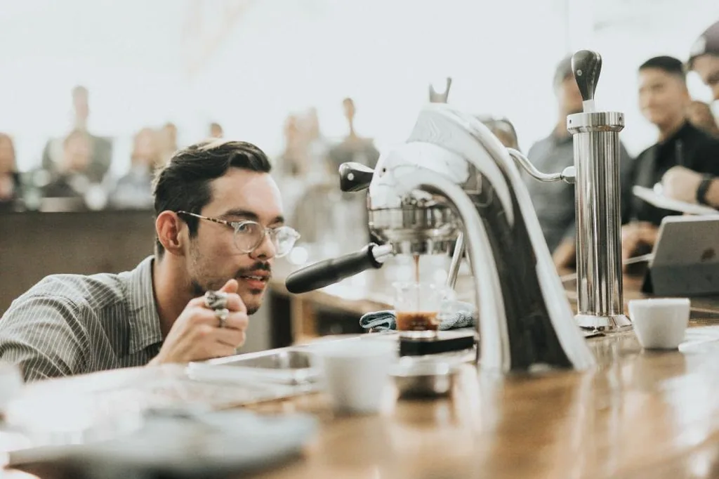 A barista pulling an espresso shot at a small cafe counter