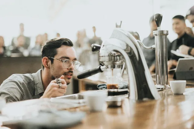 A barista pulling an espresso shot at a small cafe counter